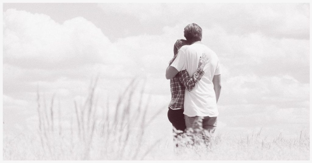 A couple hugging in a field